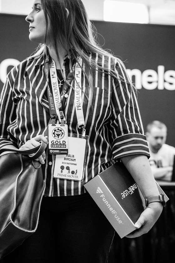 Malia Burcham at Funnel Hacking Live, Gold Certified badge, holding a Funnel Fuse box
