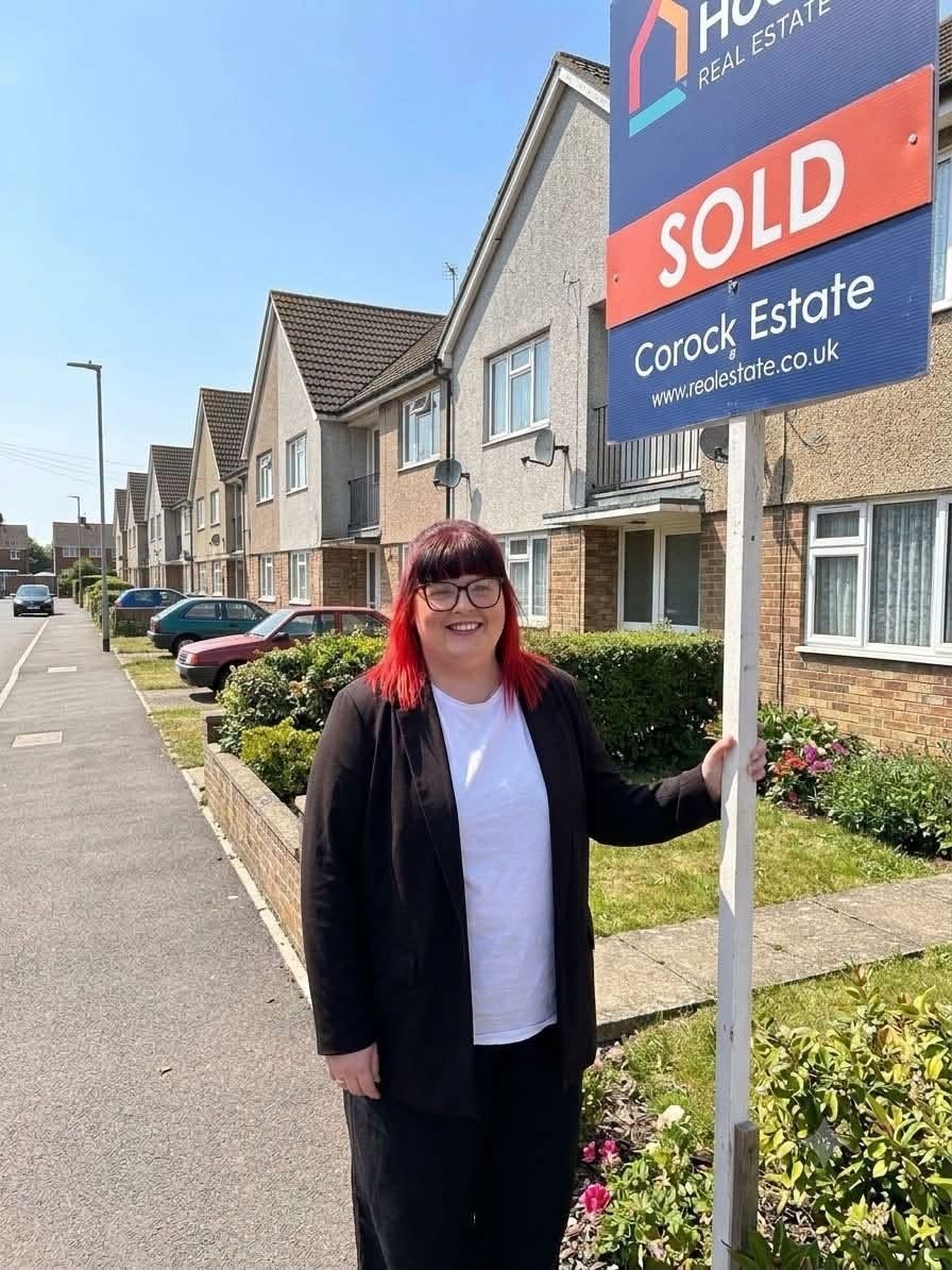 Woman beside a sold property sign