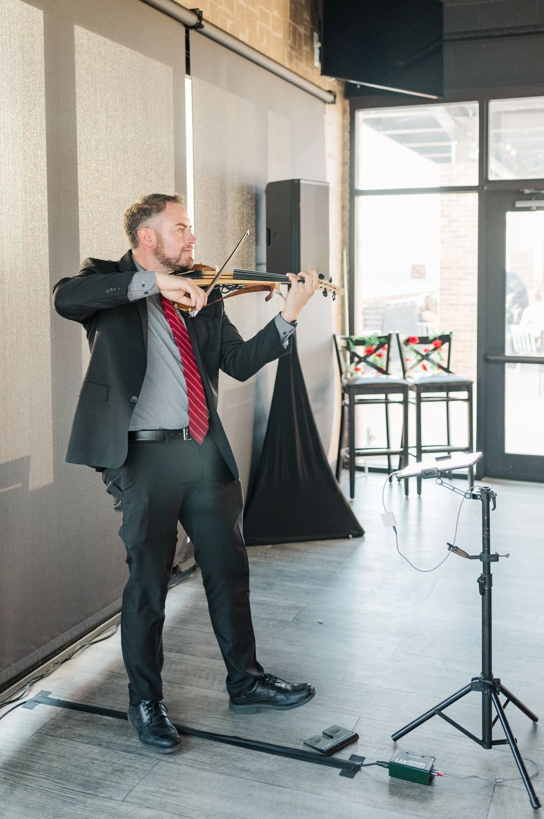 Jared Judge playing electric violin with his own speaker and music stand at an indoor event