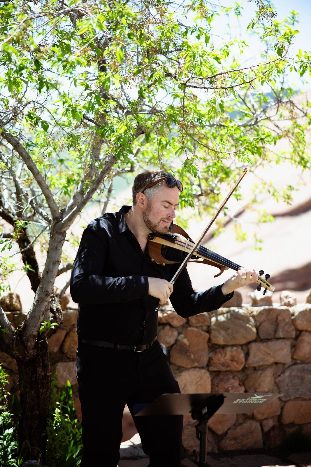 Electric violinist playing an outdoor Colorado wedding ceremony in full sun