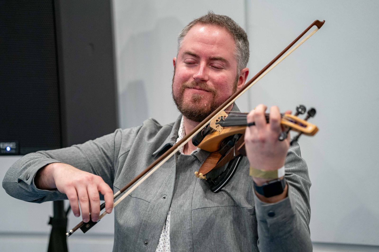 Jared Judge smiling while playing electric violin at a Denver bridal show