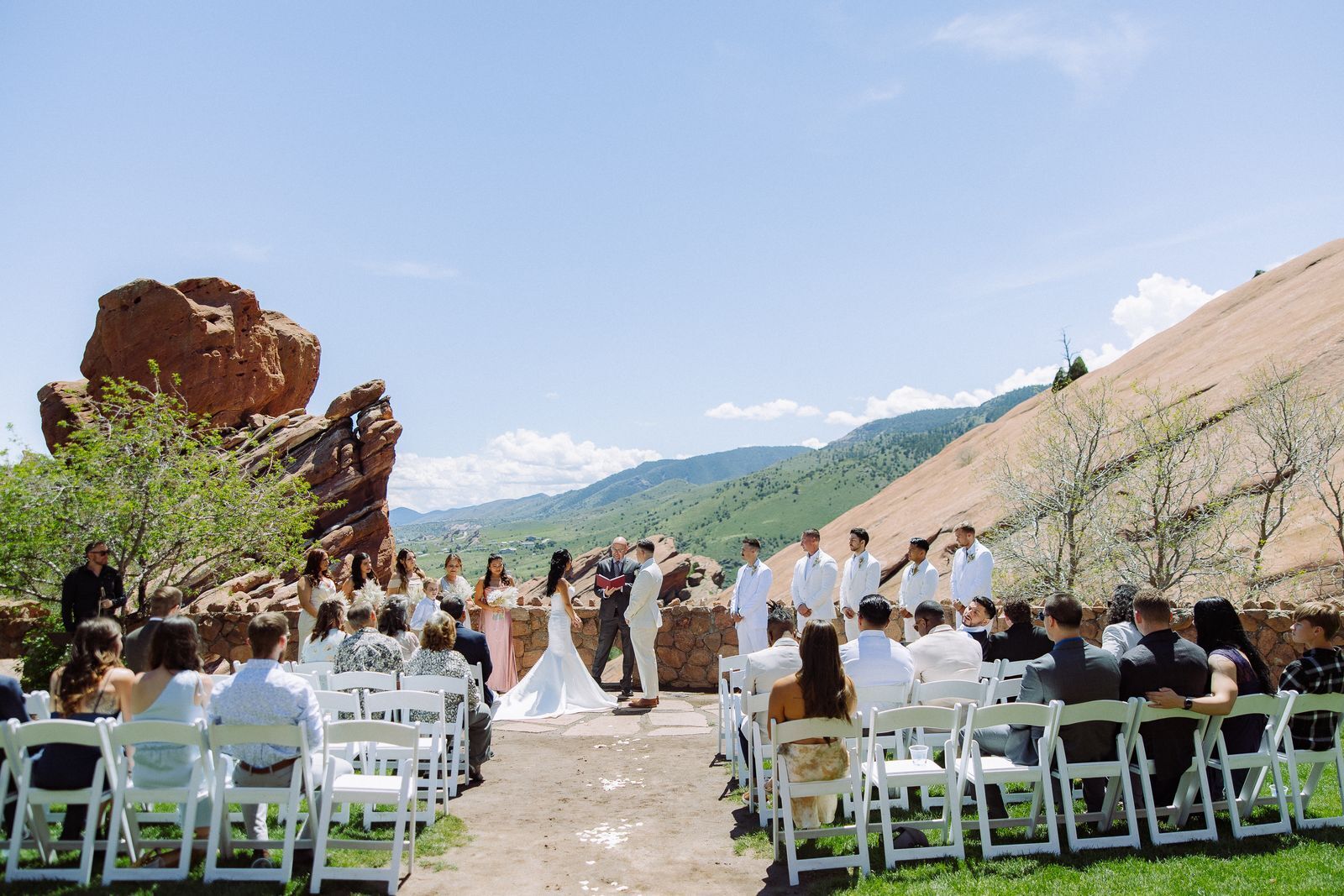 Outdoor wedding ceremony with guests seated in front of red rock formations and the Colorado foothills