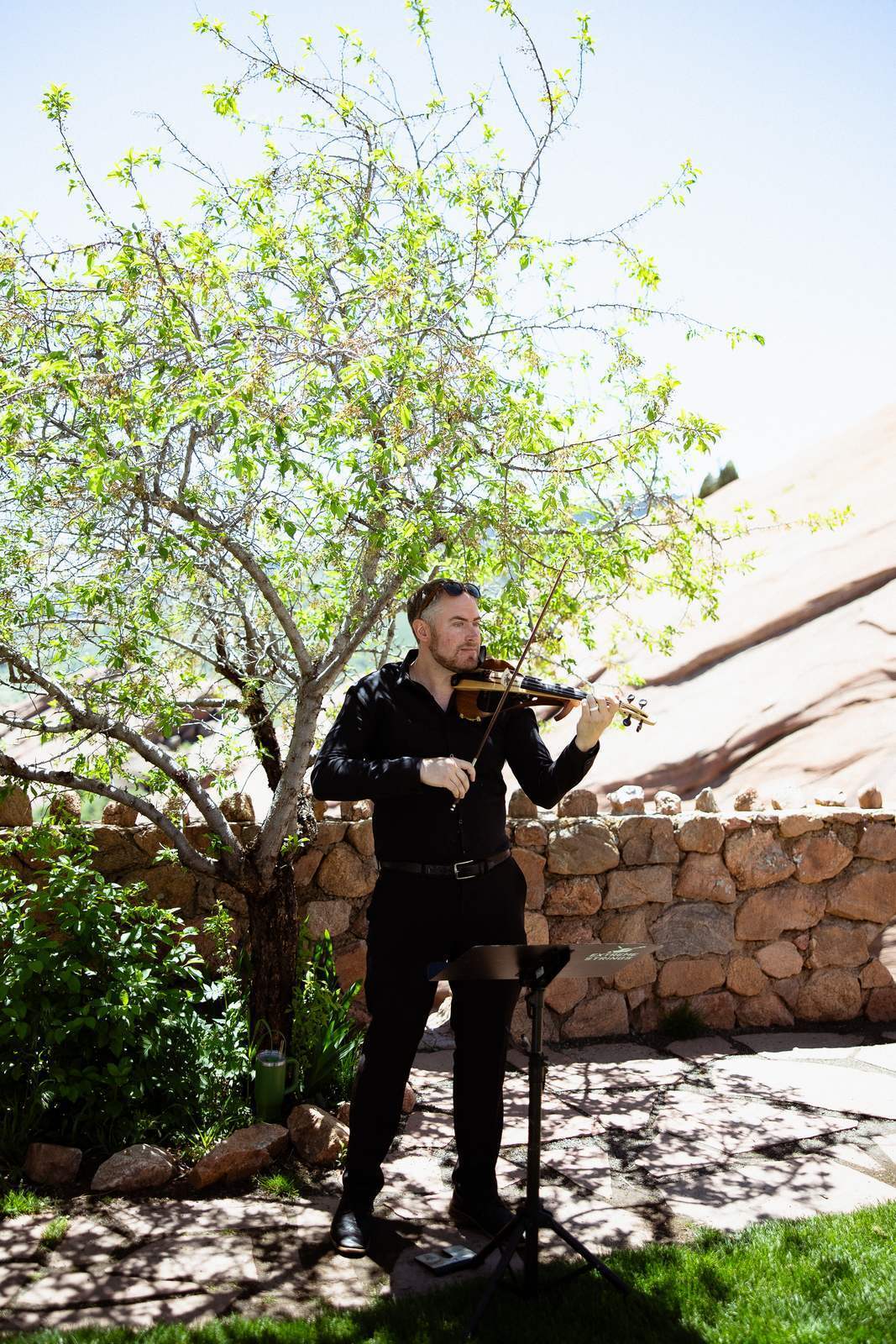Violinist Jared Judge playing an outdoor wedding ceremony beside red rock formations in Colorado